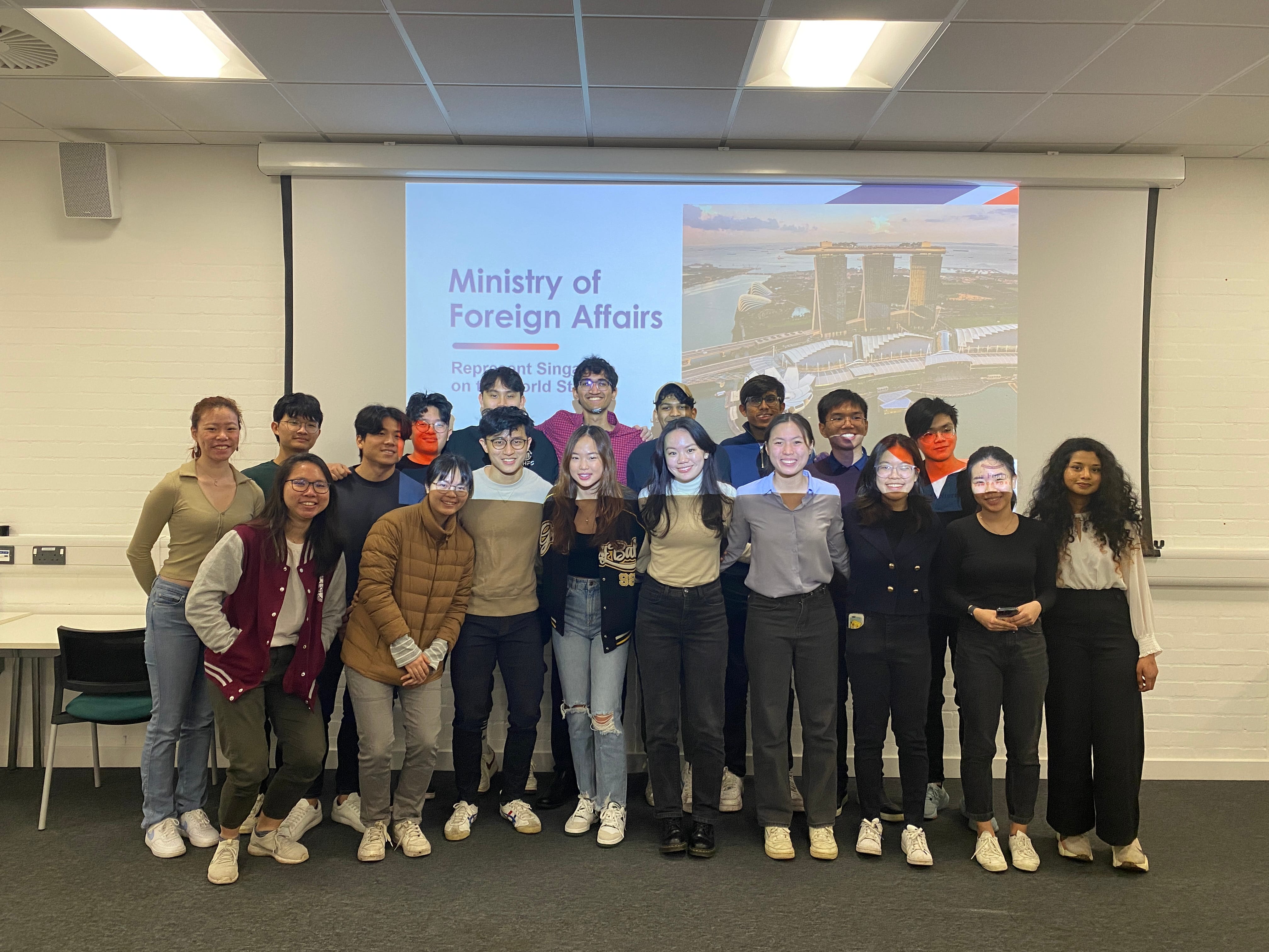 Group photo of students at MFA networking session with presentation backdrop